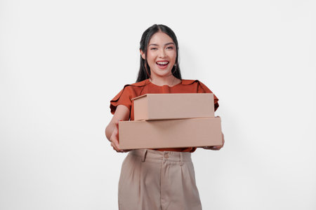 Excited young Asian woman is presenting two gift boxes with happy expression over isolated white...