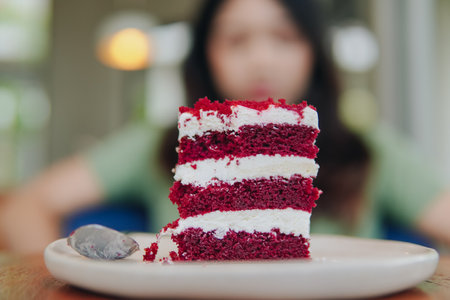 A slice of red velvet cake on a white plate. The cake is cut into layers and has a spoon on the plate with blurred background.の写真素材