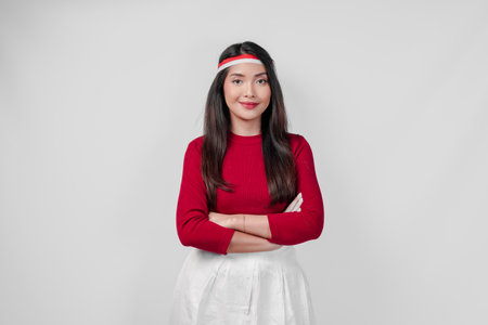 Confident young Asian woman wearing a red shirt and white skirt is standing with crossed arms. Indonesia Independence Day concept.の写真素材