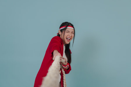 Young Indonesian woman in a red jacket is pulling on a rope, joining competition for Indonesian...