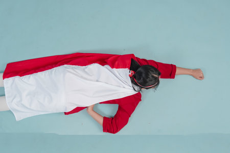 Young Indonesian woman wearing country flag on her back and raising hands superhero flying gesture....