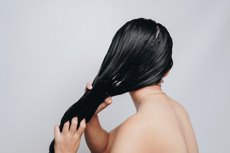 Back portrait of beautiful young Asian woman with long hair is getting her hair washed. Beauty and hair care concept.の写真素材