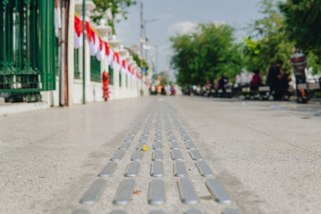 A close up of a sidewalk with a series of small metal slats. The slats are spaced out and appear to be part of a sidewalk barrier. Concept of caution and safety.の写真素材
