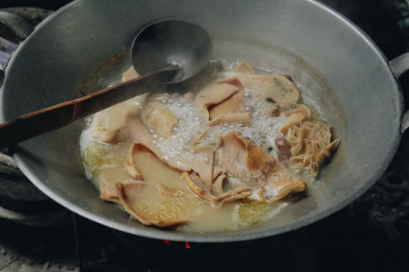 A person cooking babat or beef tripe using big wok. The process of boiling babat or beef tripe to make a dish.の写真素材