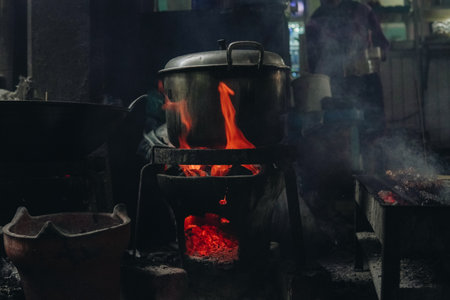 A pot of food is cooking on a stove with a lot of smoke and fire in a traditional kitchen.の写真素材