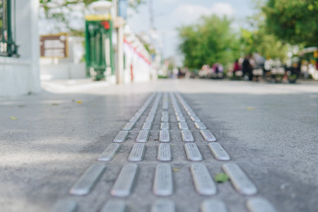 A close up of a sidewalk with a series of small metal slats. The slats are spaced out and appear to be part of a sidewalk barrier. Concept of caution and safety.の写真素材