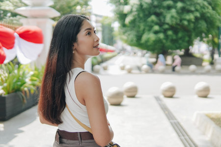 Cute young Asian woman standing on a sidewalk, enjoying the cityscape of Yogyakarta, Indonesia. Holiday and vacation concept.の写真素材