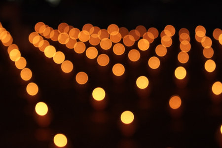 Blurry picture of many small orange lights from oil candle. The lights are arranged in a pattern and are very bright. The image has a warm and inviting mood.の写真素材