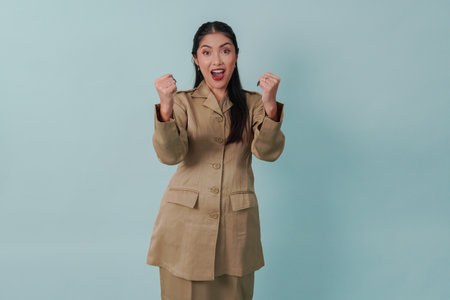 Excited Indonesian government worker woman wearing khaki uniform posing with a happy successful expression. PNS civil servant concept.の写真素材