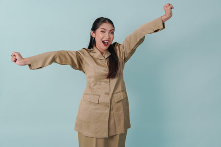 Excited Indonesian government worker woman wearing khaki uniform posing with a happy successful expression. PNS civil servant concept.の写真素材