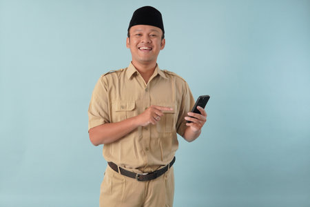 Handsome government worker man wearing khaki uniform holding smartphone while smiling. PNS and civil...