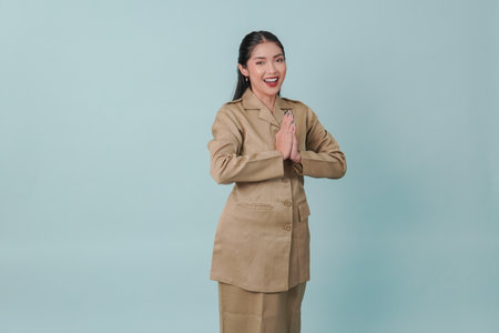 A young Indonesian government worker doing greeting gesture while smiling at camera. PNS and civil servant concept.の写真素材