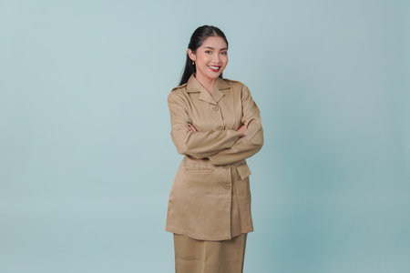 Confident government worker woman wearing khaki uniform smiling and standing with her arms crossed. PNS concept.の写真素材