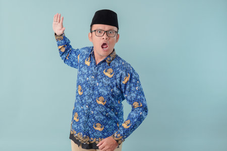 Frustrated government worker man wearing blue batik uniform doing slapping gesture with his palm.の写真素材