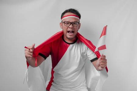 Indonesian man holding their country flag while raising fist to celebrate something. Indonesia Independence Day and sport concept.の写真素材