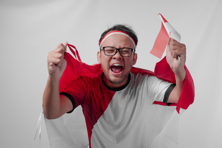 Indonesian man holding their country flag while raising fist to celebrate something. Indonesia Independence Day and sport concept.の写真素材