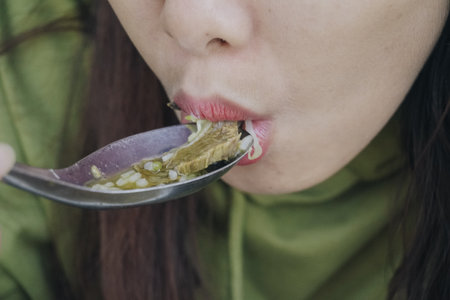 Close up portrait of Asian woman using spoon to eat Indonesian traditional cuisine named soto soup mainly composed of broth, meat, and vegetables.の写真素材