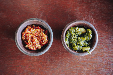 Two bowls of Indonesian traditional sambal or chili sauce, left one is made using red chili and the right one using green chili.の写真素材