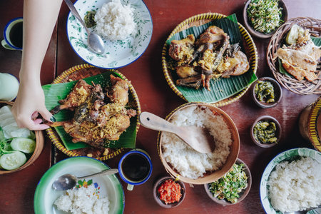 A table with a variety of Asian food, including rice, meat, and vegetables, set with plates, bowls, and utensils.の写真素材