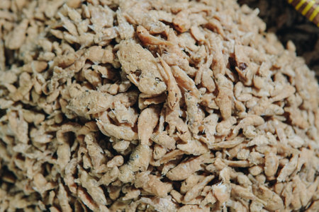 A plate of fried anchovies is piled high in a red basket displayed in one of the stalls traditional...