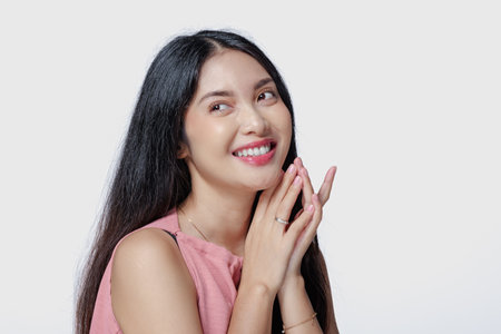 Excited young Asian woman wearing pink dress with a joyful expression, isolated by white background.の写真素材