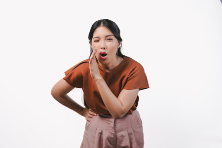 Surprised Asian woman in a brown shirt gesturing whisper to someone with her hand, isolated by white...