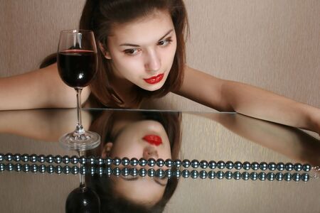 Portrait of the girl with a glass of wine and reflection in a mirror.の写真素材