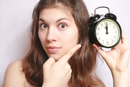 Portrait of the girl showing a finger on an alarm clock.の写真素材