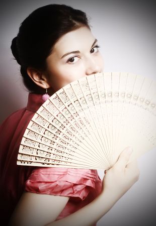 Portrait of the girl in pink to a blouse and a fan in a hand.の写真素材