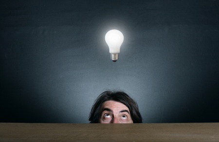 Man looking up at the burning light bulb.の写真素材