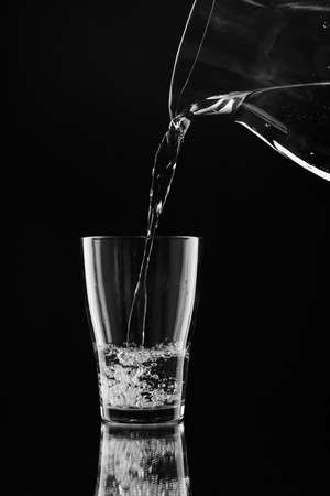 Water pitcher pouring a glass of fresh waterの写真素材