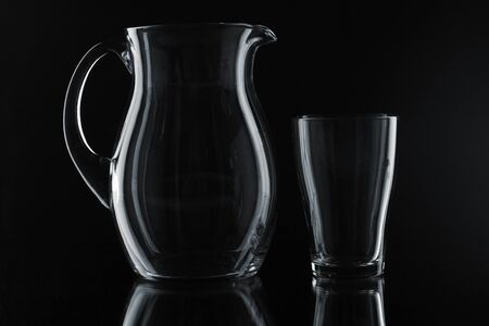 Glass pitcher and glass on a black background.の写真素材