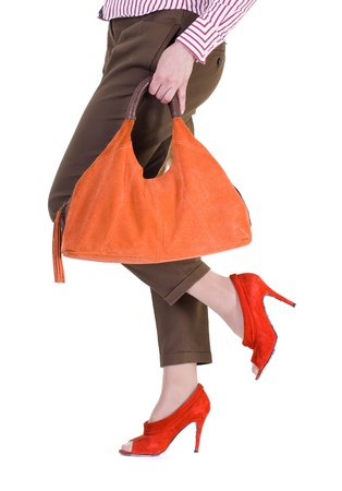 A close-up of a chic red handbag along with sexy female legs wearing elegant red shoes.の写真素材