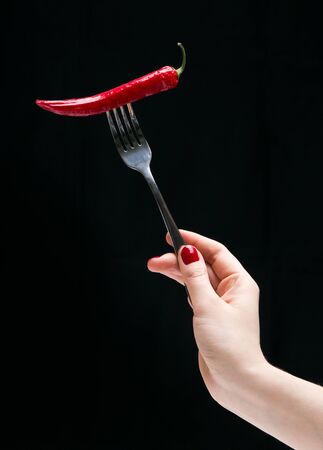 Hot pepper on the fork in the female hand.の写真素材