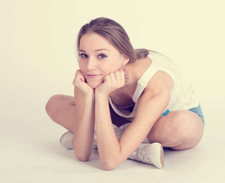 Beautiful happy blond girl sitting on a white background.の写真素材