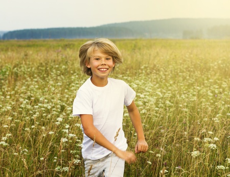 Happy boy running on summer fieldの写真素材