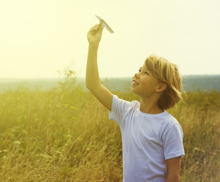 Happy kid playing with toy airplane against blue summer sky background の写真素材
