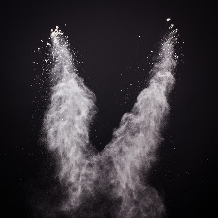 Freeze motion of white dust explosion isolated on black backgroundの写真素材