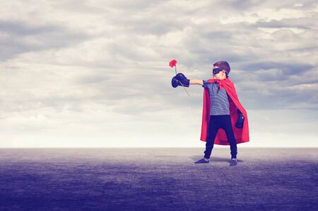 Superhero kid wearing boxing gloves and flower outdoors.の写真素材