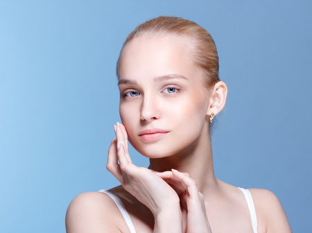 Beautiful Young Woman with Clean Fresh Skin touch own face . Facial treatment . Cosmetology , beauty and spa .の写真素材