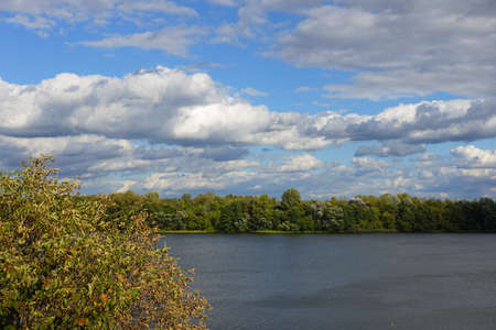 Landscape with autumn tree and clouds above the river