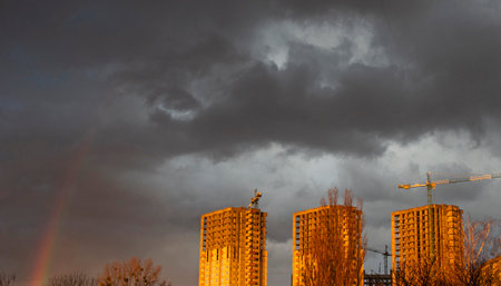 New buildings illuminated by the evening sun against the background of a sky with thundercloudsの写真素材