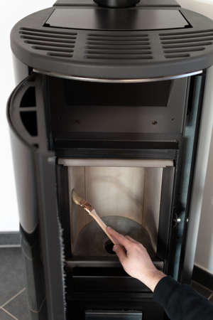Man cleaning pellet stove with brushの写真素材
