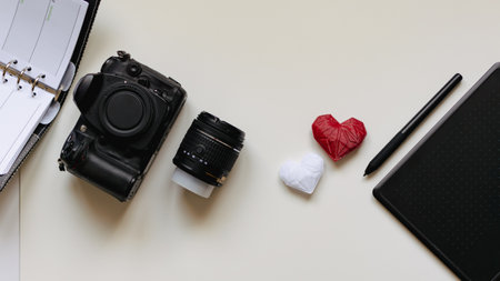 Graphic designer workstation with dslr, lens, diary, stylus and heart printed in 3dの写真素材