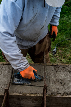 Bricklayer spreading concrete with a trowel and level to build a wall at a construction site