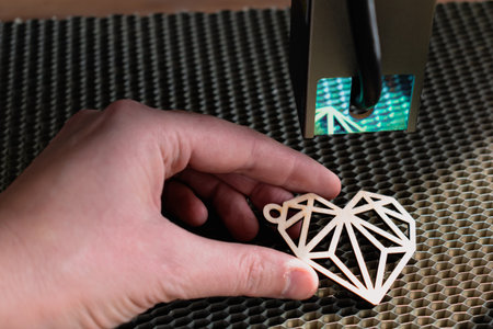 Laser engraving and cutting, woman holding an example of a cut out wooden heart