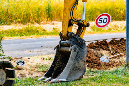 Arm of a mini digger and bucket with a speed limit sign at 50, road signの写真素材