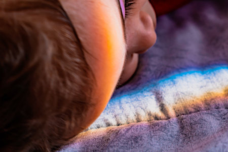 Baby resting in bed with rainbow on headの写真素材