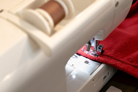 Man using a sewing machine with a red garment, for repair work, customization, creation, upcyclingの写真素材