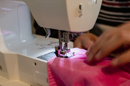 Man using a sewing machine with a pink garment, for repair work, customization, creation, upcyclingの写真素材